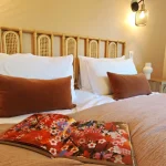 Bamboo Suite Cozy queen-size bed, terracotta cushions and open book, at Numa House