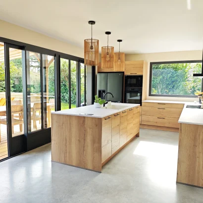 Vue complète de la cuisine ouverte de Numa House, avec ilôt central et vue piscine