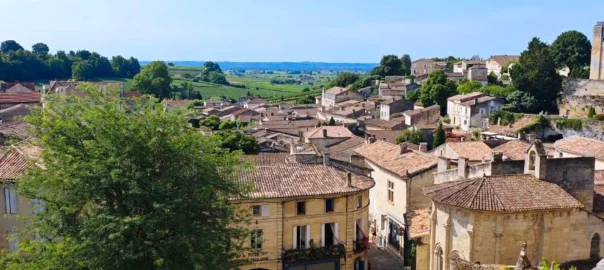Vue plongeante sur la place du village médiéval de Saint-Emilion, pierre blonde et grand ciel bleu